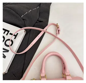 Detail of pink lychee leather handbag with adjustable strap and light gold hardware