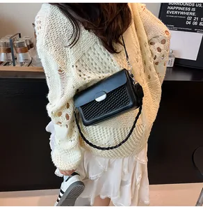 Detail showing the woven texture and silver metal buckle on a black leather square bag