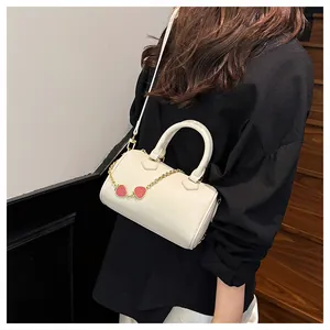Detail of white cylinder Boston bag with lychee texture and red strawberry charms