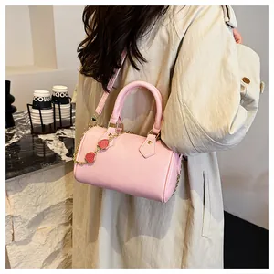 Pink Boston bag with strawberry charm shown in a chic cafe setting on a marble table