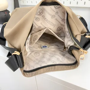 Spacious khaki nylon tote bag interior with multiple compartments and gold hardware