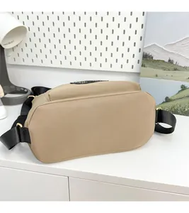 Detail of khaki nylon tote bag with wide black strap and gold metal buckle hardware