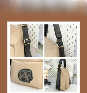 Detail of beige tote bag featuring sparkling elephant rhinestone patch and black wide strap