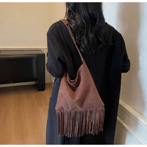 Vista detallada del bolso tote de ante marrón con flecos largos y diseño de estilo retro