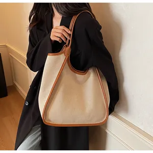 Détail d'un sac cabas minimaliste montrant la toile beige et la bordure en cuir marron