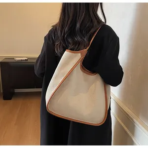 Vue détaillée d'un sac cabas en toile beige avec bordure en cuir marron sur mannequin