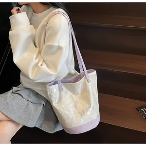 Dettaglio del motivo a farfalla 3D su borsa a secchiello crema con finiture viola
