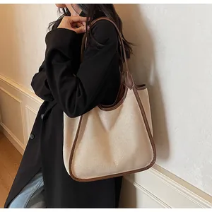 Vue détaillée d'un grand sac cabas en toile beige avec finitions en cuir marron sur l'épaule
