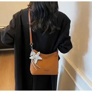 Brown frosted underarm bag detail featuring a silver star pendant on a retro shoulder bag
