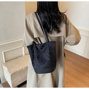 Borsa a secchiello nera a pois indossata da una modella con trench beige per un look casual