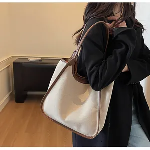 Détail d'un grand sac fourre-tout en toile beige avec bordure en cuir marron sur modèle