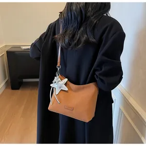 Detail of a brown matte shoulder bag featuring an oversized silver sequin star charm