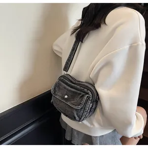 Detailed view of grey washed denim crossbody bag with vintage silver metal hardware