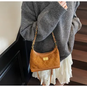 Detail showing brown suede quilted pattern with gold twist lock and metal chain strap