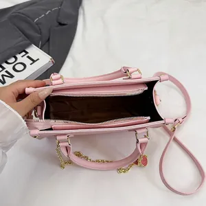 Sac à bandoulière rose avec intérieur multicouche et breloque cœur sur chaîne dorée