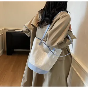 Dettaglio della borsa a secchiello floreale bianca e blu indossata da una modella