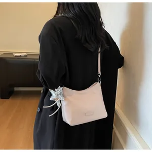 Detail of light pink shoulder bag with star charm and metallic brand plate on faux leather