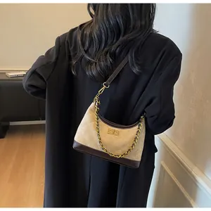 Quilted beige suede underarm bag with brown leather trim and golden chain strap on a model