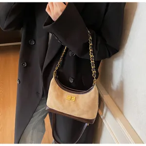 Close-up of quilted suede shoulder bag with gold twist lock and chain strap details