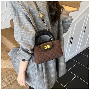 Detail view of brown quilted crossbody bag with gold chain and decorative ball