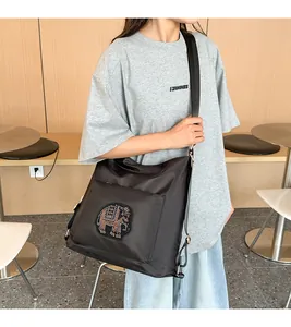 Detail of black nylon hobo bag featuring elephant embroidery and wide shoulder strap