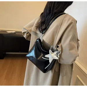 Detail of black glossy hobo bag featuring a large silver star charm and embossed logo
