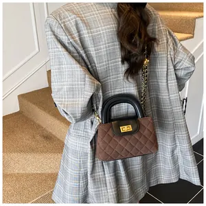 Detail of quilted suede crossbody bag featuring gold twist lock and woven chain strap