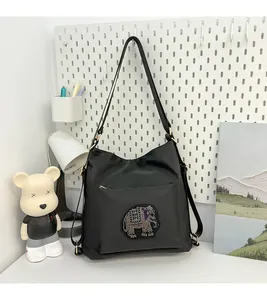 Detail of black tote bag featuring sparkling rhinestone elephant patch and zip pocket