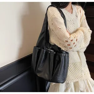 Detail of black leather tote bag featuring functional multi-pockets with rivet studs