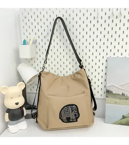 Detail of khaki fabric tote bag with rhinestone elephant patch and black shoulder strap