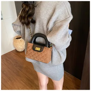 Close-up of brown suede crossbody bag featuring quilted patterns and gold metal lock
