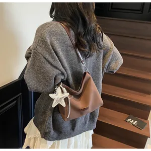 Brown matte leather underarm bag with silver star charm shown from a back view