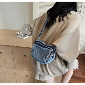 Detail view of a vintage blue denim crossbody bag worn by a model in a home office setting
