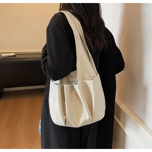 Close-up of beige soft leather tote bag showing side pleated pockets and smooth texture