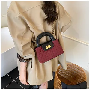 Detail shot of wine red quilted chain bag with gold twist lock and black leather handle