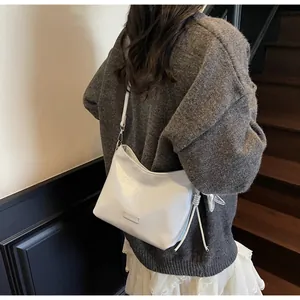 Back view of a chic white glossy shoulder bag with silver bow charm and drawstring detail