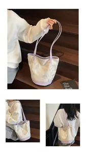 Dettaglio della borsa a secchiello crema con bordo viola ed elegante stampa a farfalla