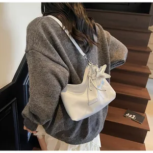 Detail of white PU leather underarm bag with silver star charm and embossed logo detail