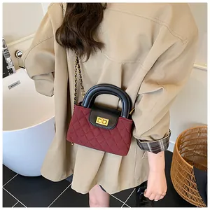 Detail view of quilted burgundy mini bag with black handle and gold-tone turn-lock