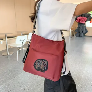 Fashionable maroon tote bag with rhinestone elephant patch shown on a shoulder