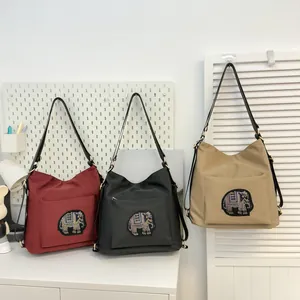 Three large tote bags in burgundy, black, and khaki with sparkling elephant patch details