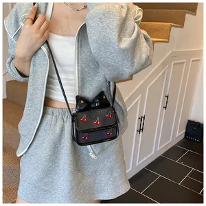 Close-up of mini black crossbody bag featuring a large leather bow and cherry patterns