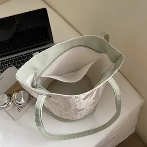 Borsa a secchiello verde e crema con motivi floreali e vista dall'alto dell'interno spazioso