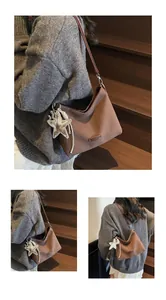 Close-up of brown matte faux suede shoulder bag with star pendant and sleek strap detail
