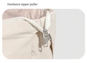 Detail showing the silver metal zipper puller and white zipper on the beige nylon tote bag