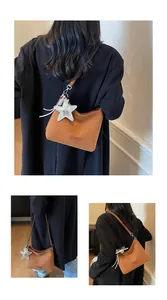 Detailed close-up of brown frosted suede underarm bag featuring a silver star charm