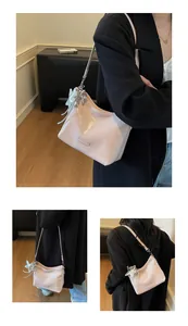 Detail of light pink glossy leather underarm bag with silver star charm and metal logo