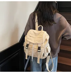 Detail view of cream nylon backpack with textured fabric and buckled flap on a model