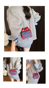 Detailed view of mini denim crossbody bag with cherry embroidery and red bow