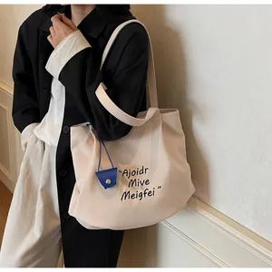 Canvas tote bag with black artistic lettering and blue leather charm detail
